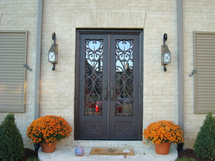 portico di una casa di campagna con porta d'ingresso in ferro battuto e vetro