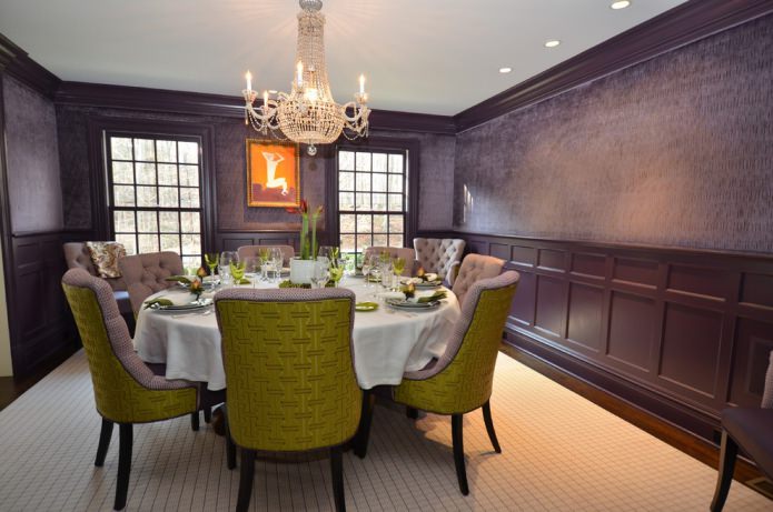 sala da pranzo con carta da parati viola scuro e sedie verdi e lilla