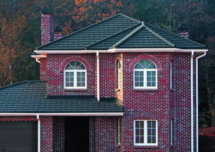 una casa fatta di mattoni rosso scuro con un tetto nero