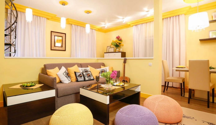 Soggiorno giallo chiaro con cuscini multicolori e pouf lavorati a maglia